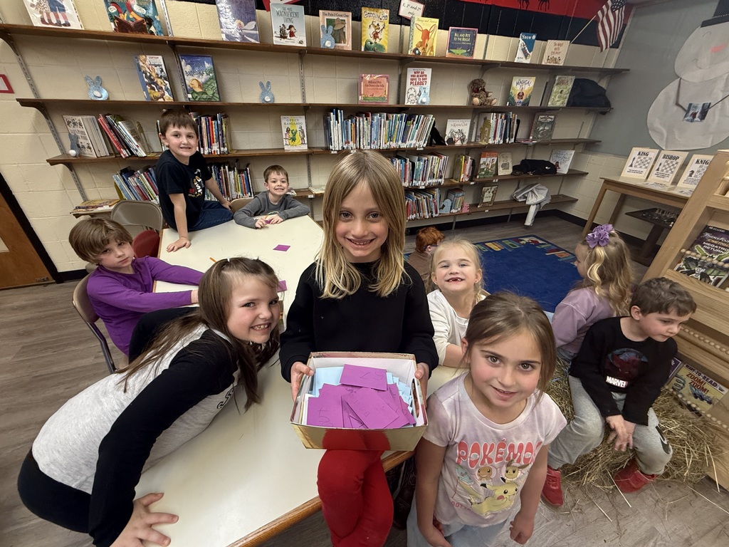 A small, soft bunny with fluffy fur and long ears, gently being held or petted during a classroom visit.