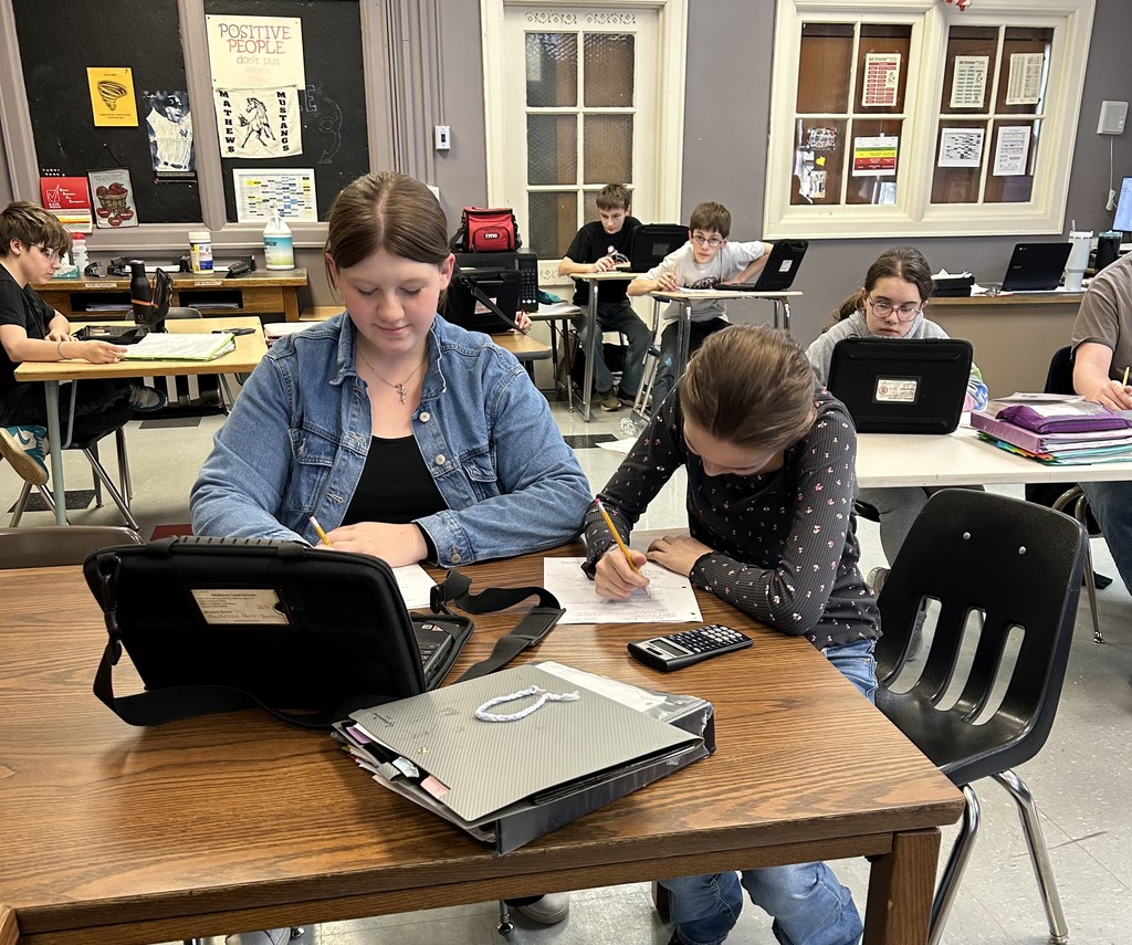 Students work on math assignments involving equations, volume, and probability in a classroom setting.