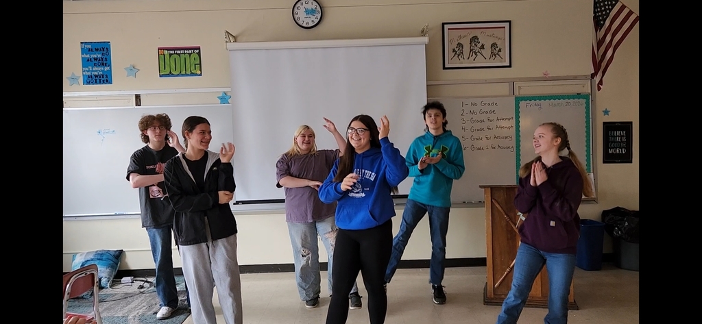 Students performing a song and dance in a classroom setting.