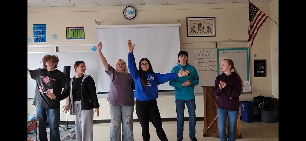 Students performing a song and dance in a classroom setting.