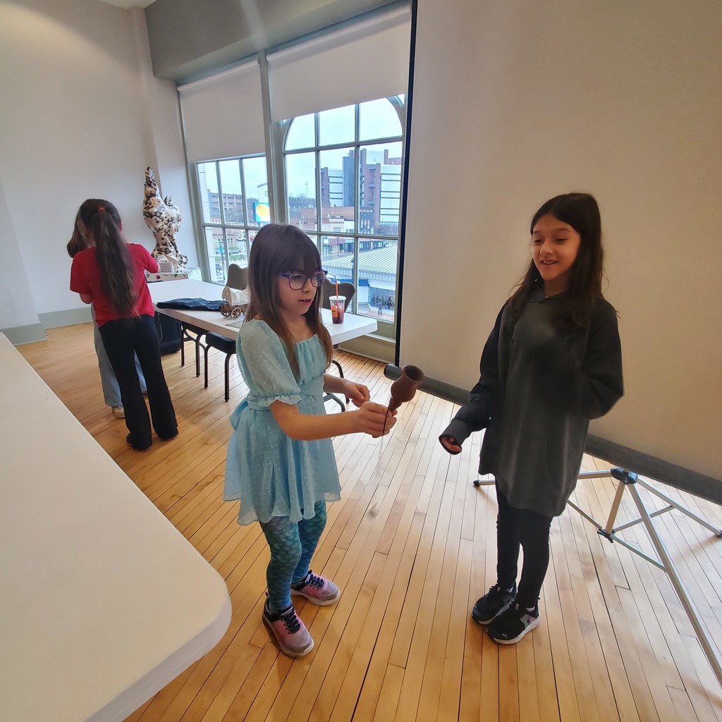 Group of elementary students touring museum exhibits and viewing artwork during a school field trip.