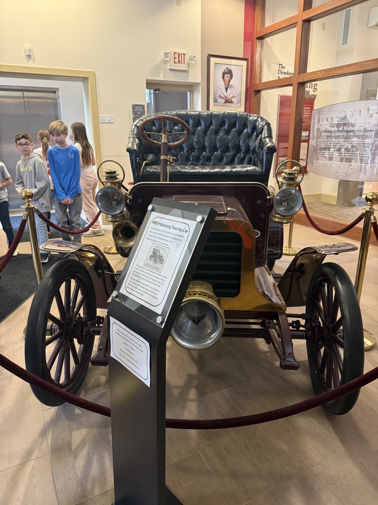 Group of elementary students touring museum exhibits and viewing artwork during a school field trip.