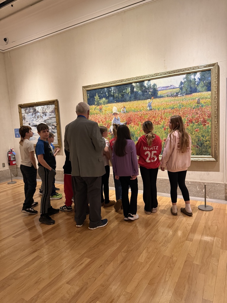 Group of elementary students touring museum exhibits and viewing artwork during a school field trip.