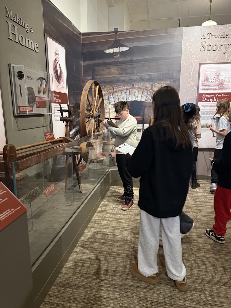 Group of elementary students touring museum exhibits and viewing artwork during a school field trip.