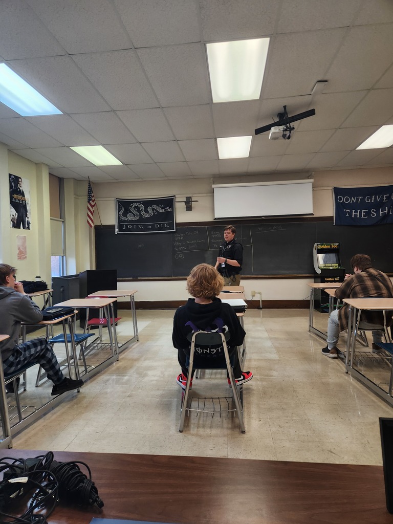 Law enforcement professionals speaking to high school students in a classroom
