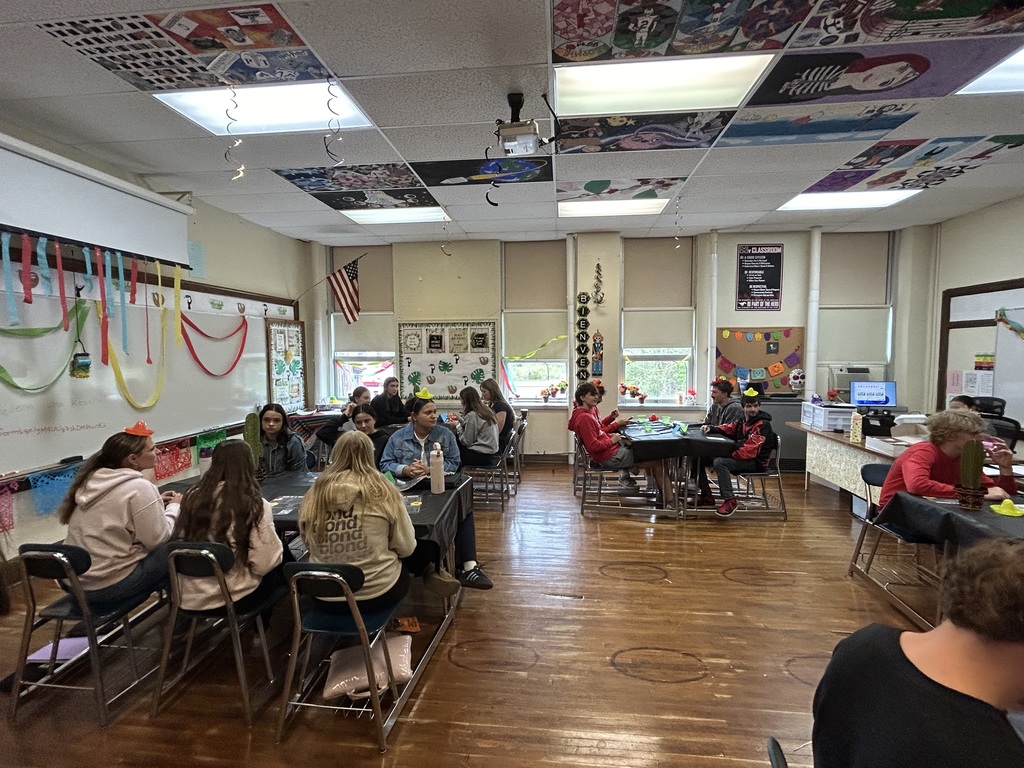 Spanish II students serving authentic Hispanic food to classmates and staff during a classroom restaurant project with menus and dine-in dining tables.