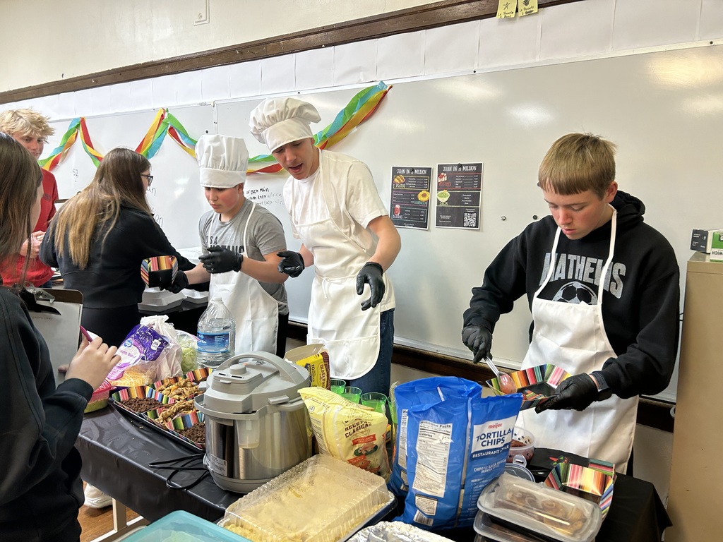 Spanish II students serving authentic Hispanic food to classmates and staff during a classroom restaurant project with menus and dine-in dining tables.