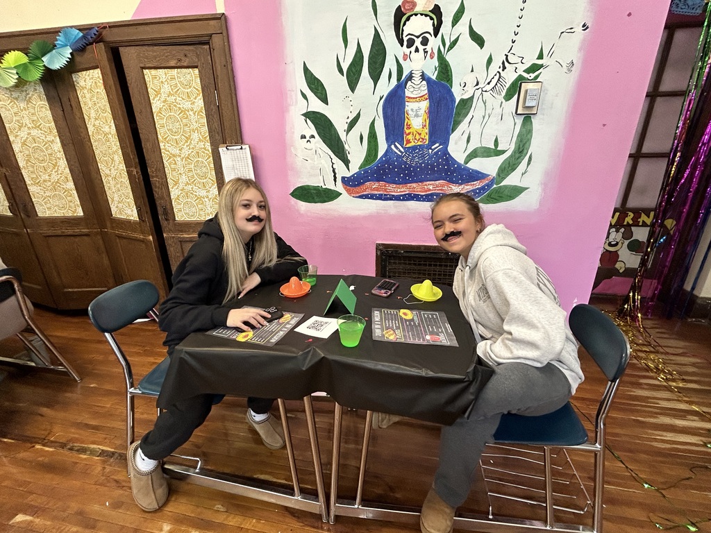 Spanish II students serving authentic Hispanic food to classmates and staff during a classroom restaurant project with menus and dine-in dining tables.