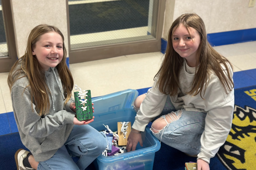 two mms 6th grade industrial tech students next to a box of shoe tying projects