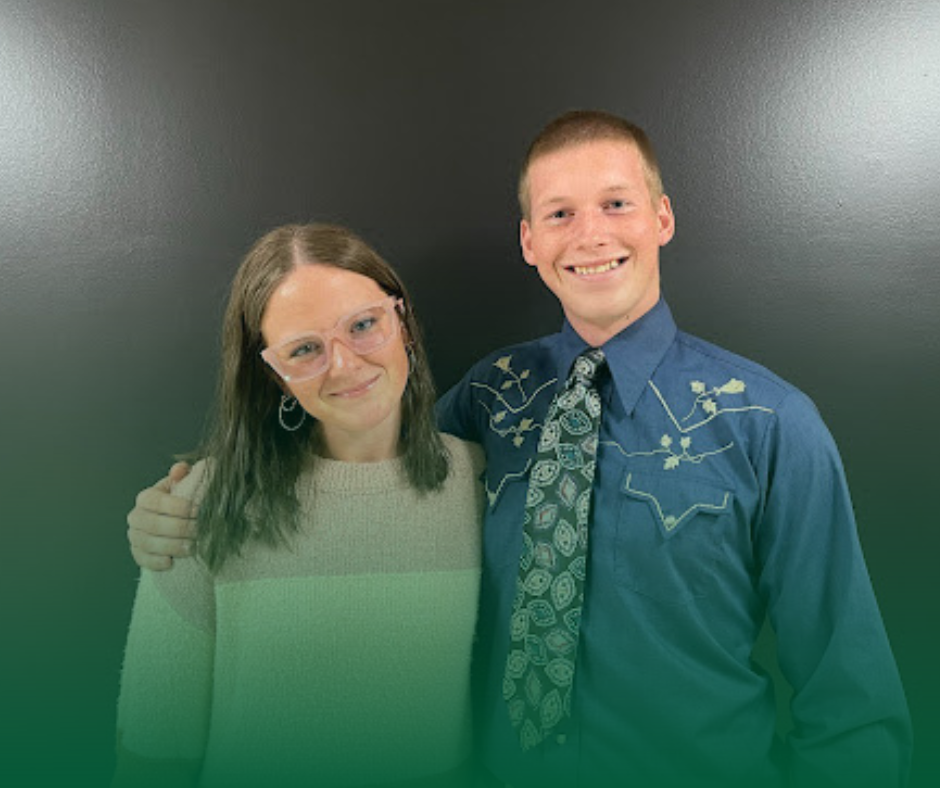 Photo of the Rotary Students of the Month from MHS. They are in front of a black background and one has his arm around the other. One is wearing a sweater and the other a dress shirt and tie.