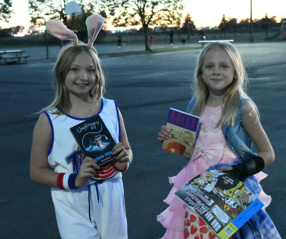 Two students dressed in costumes holding books at the Williams Elementary Trunk or Treat