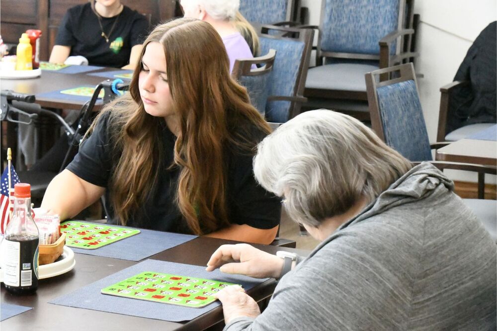MHS student playing bingo with an assisted living resident during green and gold day