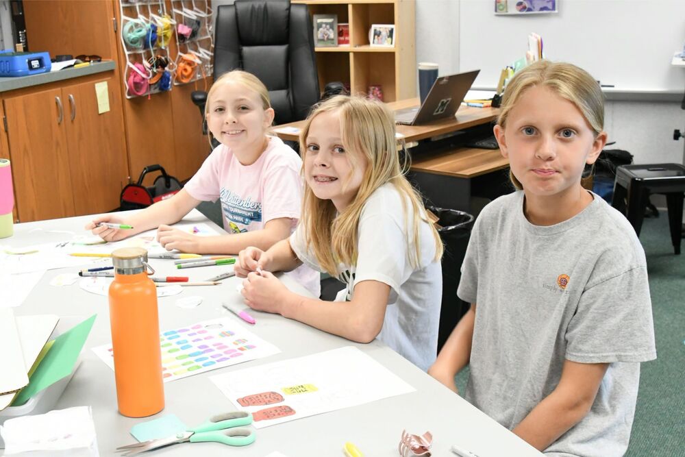 three students working at a table with supplies