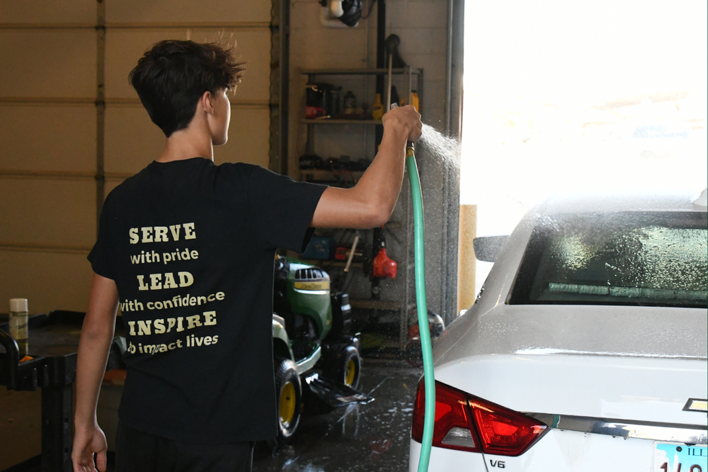 Student washing a car on Green & Gold Day