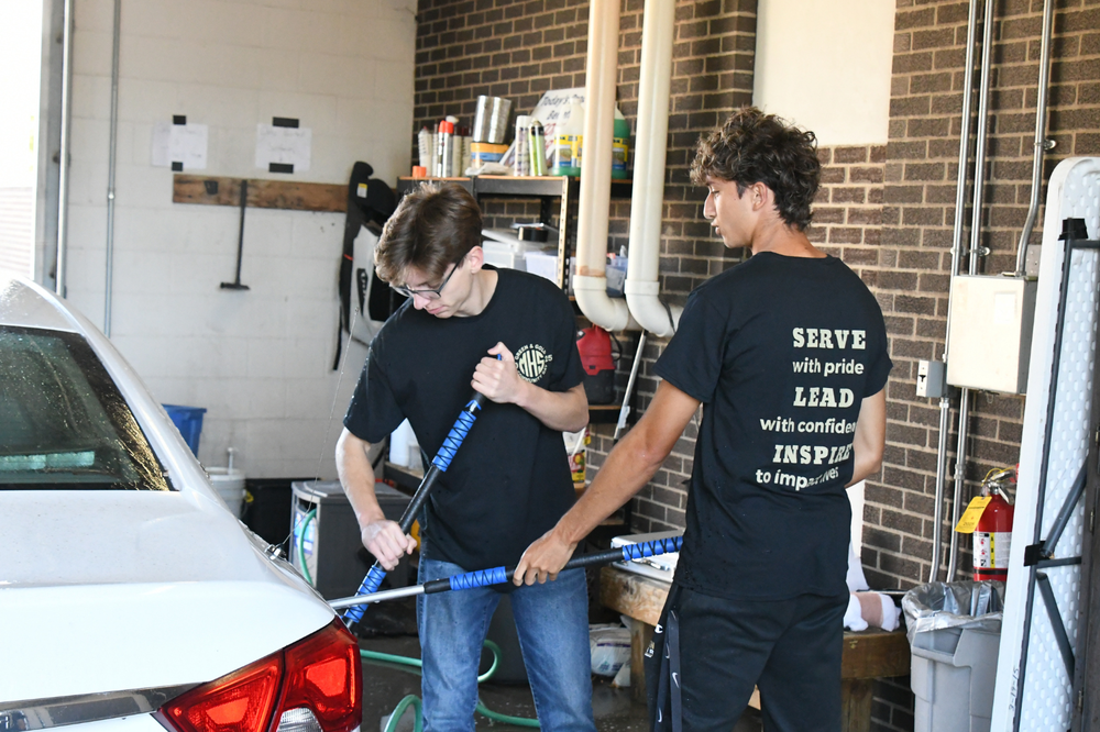 Green & Gold Day. 2 students washing a car