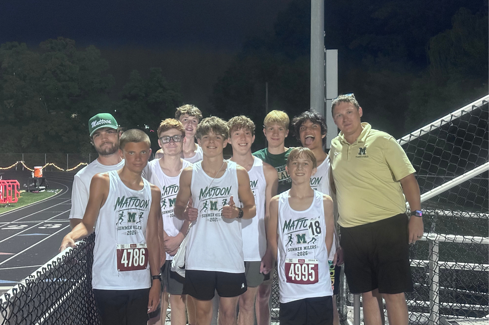 7 track runners from MHS and three coaches standing on bleachers next to a track at a recent tournament