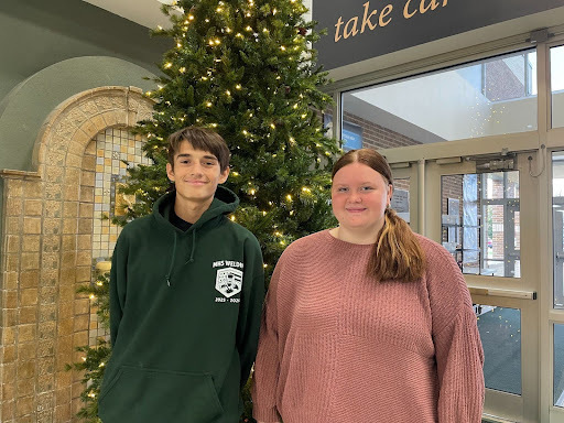 Photo of two MHS students selected as the November Rotary Students of the Month. They are inside standing next to a Christmas Tree.