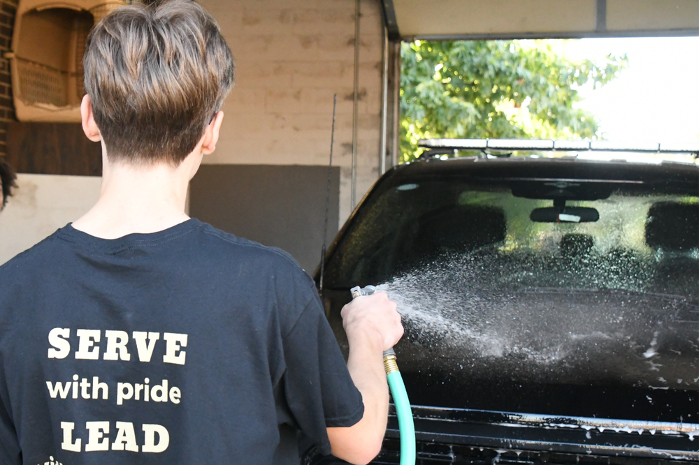 MHS student washing a car with a hose