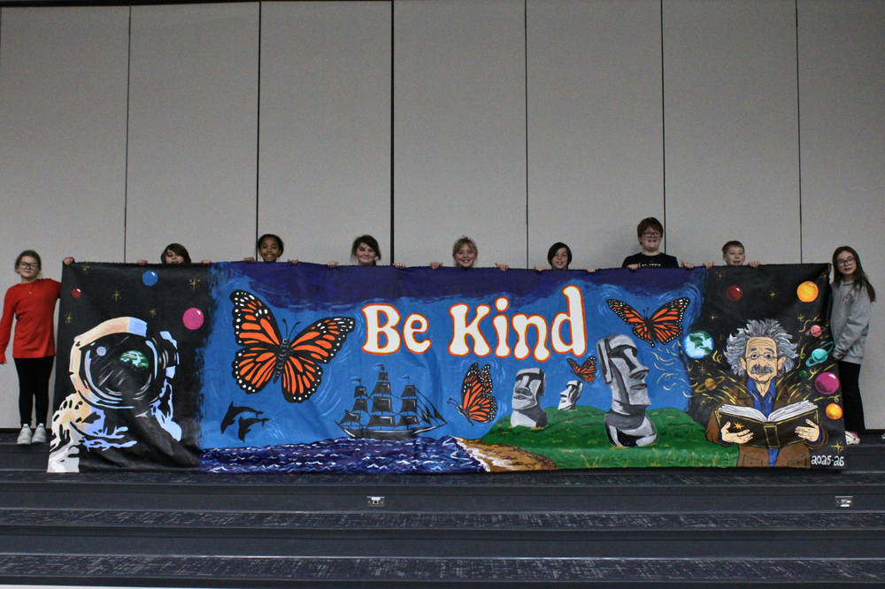 5th Grade Riddle Mural -students are holding it up