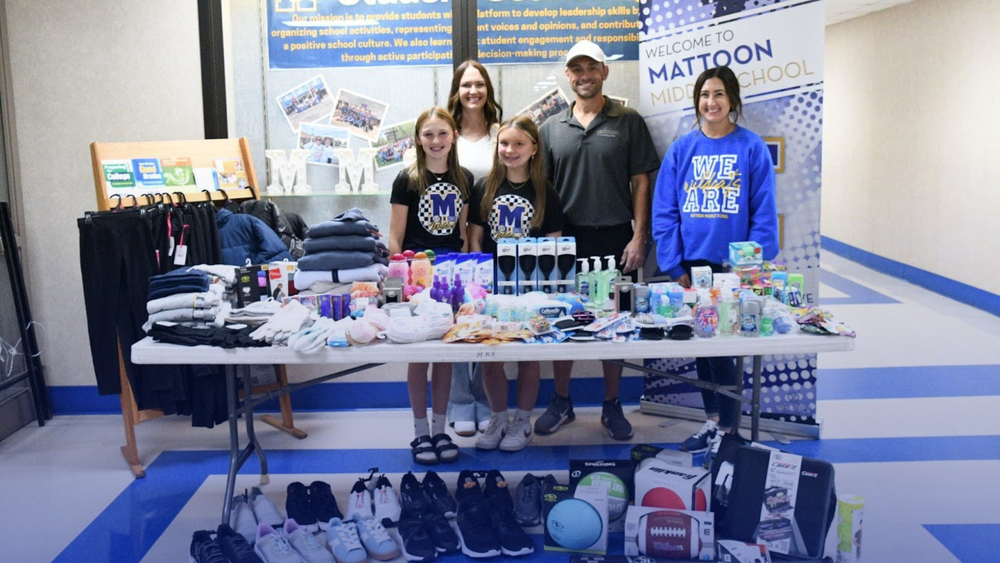 Two students, a staff member, and two local business owners who donated to MMS standing in front of a table of donations
