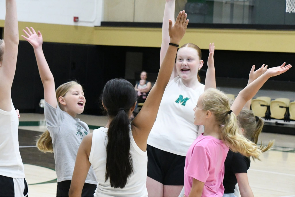 MHS Dance camp. Students in a huddle with hands up
