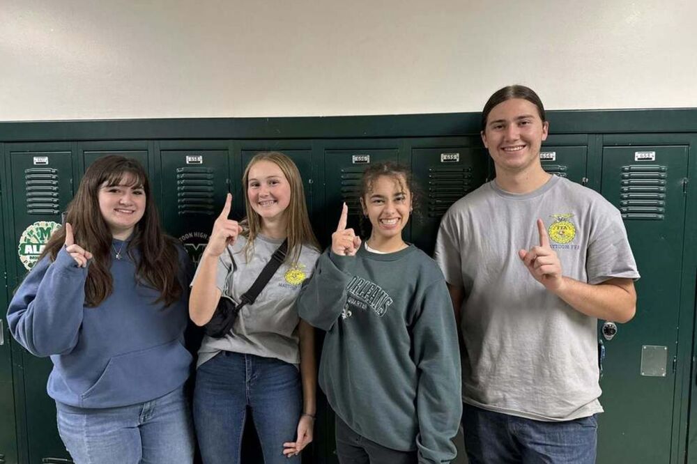 four mhs students holding up the #1 sign standing in front of lockers