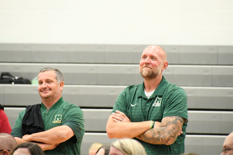 two staff members standing and smiling at the back to school breakfast