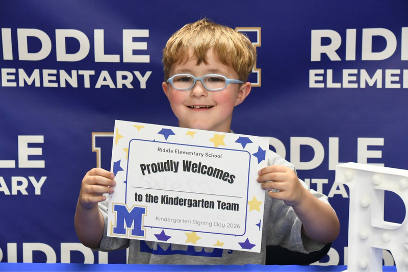 Kindergartener holding up a certificate at kindergarten signing day