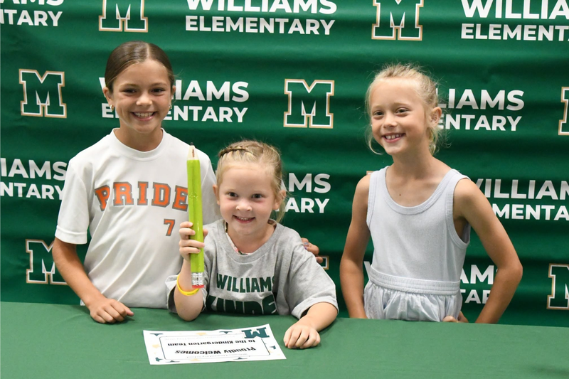 three students at kindergarten signing day posing at the photo booth