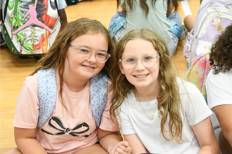 Two students posing in the gym with backpacks on