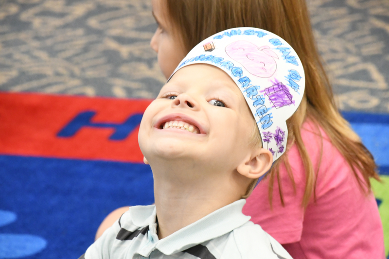 kindergartener posing for a photo with a art crown on head