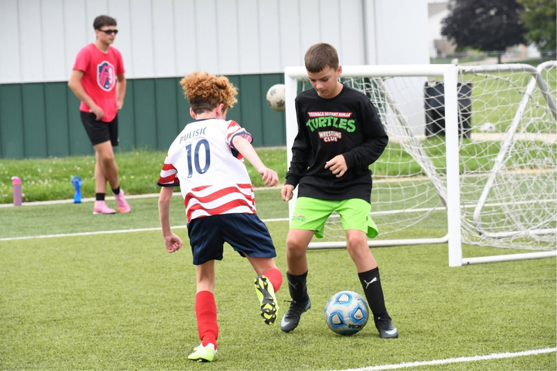 Soccer summer camp . 2 students kicking a soccer ball