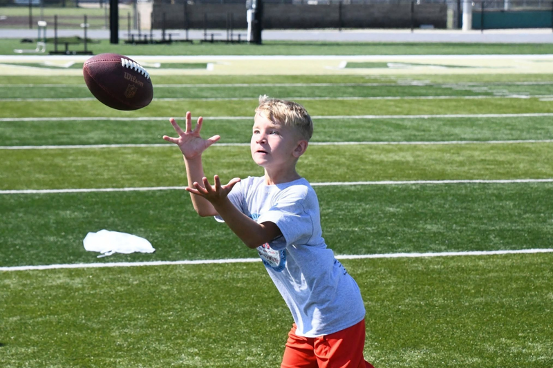 MHS youth summer camp. Student catching a football.
