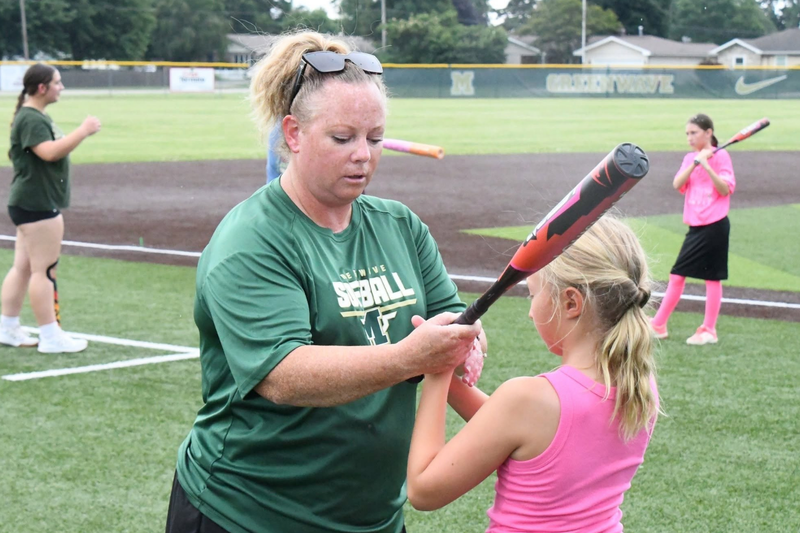 MHS youth summer camp. Softball coach helping a student hold a bat