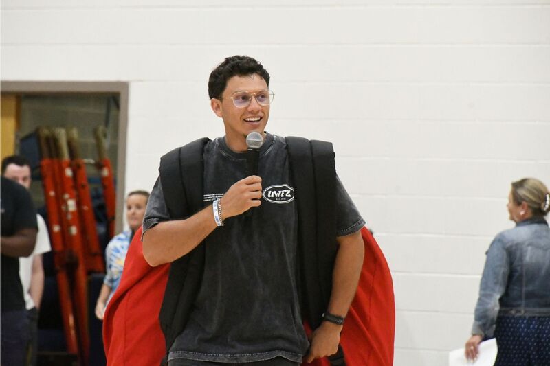 Sam Demma with a giant backpack on his back speaking to a group of students