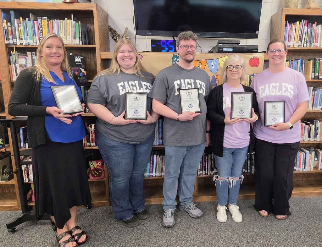 The photo shows teaching staff at Mayflower High School with plaques displaying their continuous years of service in the school district.