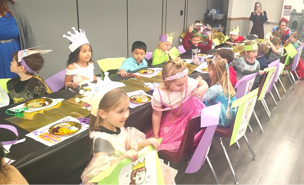 5K students dressed with king and queen crowns and seated at a long table in the auditorium with placemats