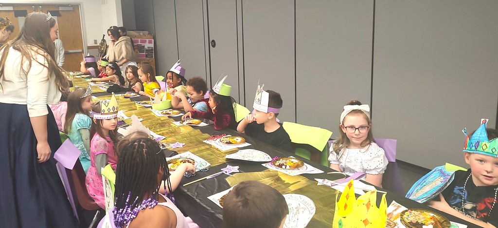 5K students dressed with king and queen crowns and seated at a long table in the auditorium with placemats