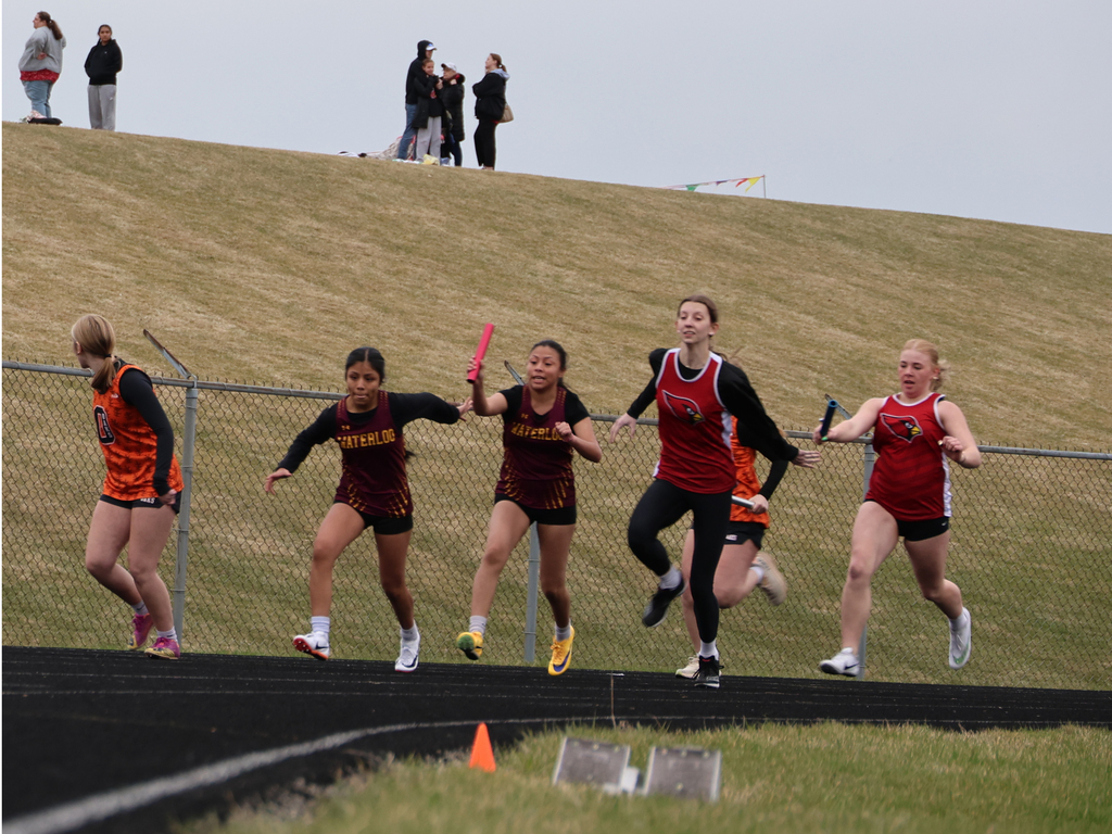 Mayville Track team Berry Invite runners on track with green grassy hill in background