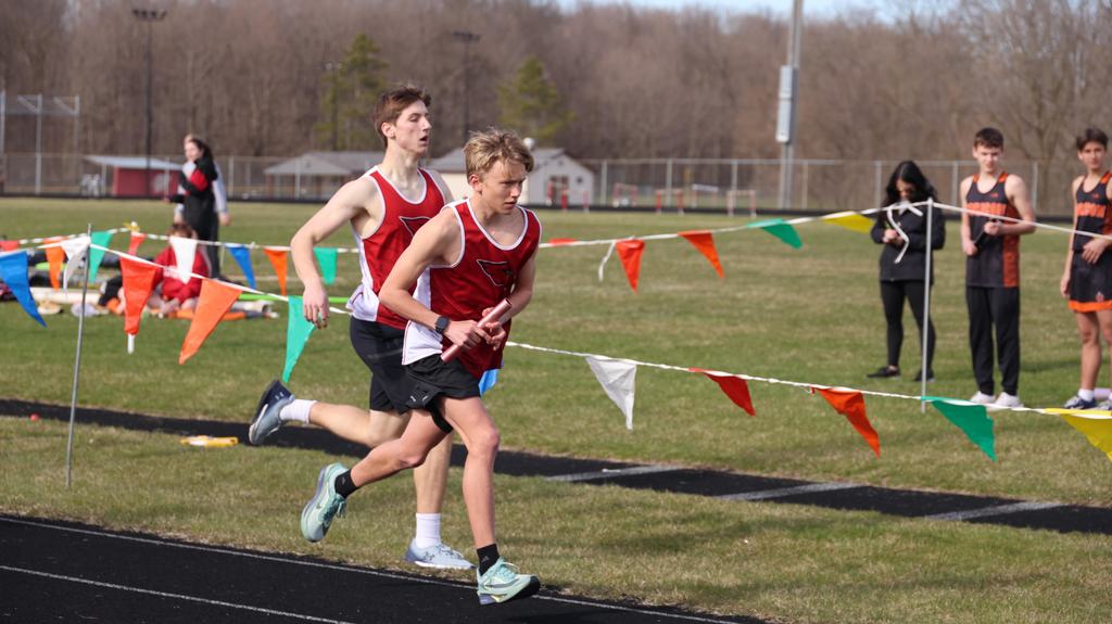 Mayville Track team Berry Invite runners on track with green grass infield and other track participants in background