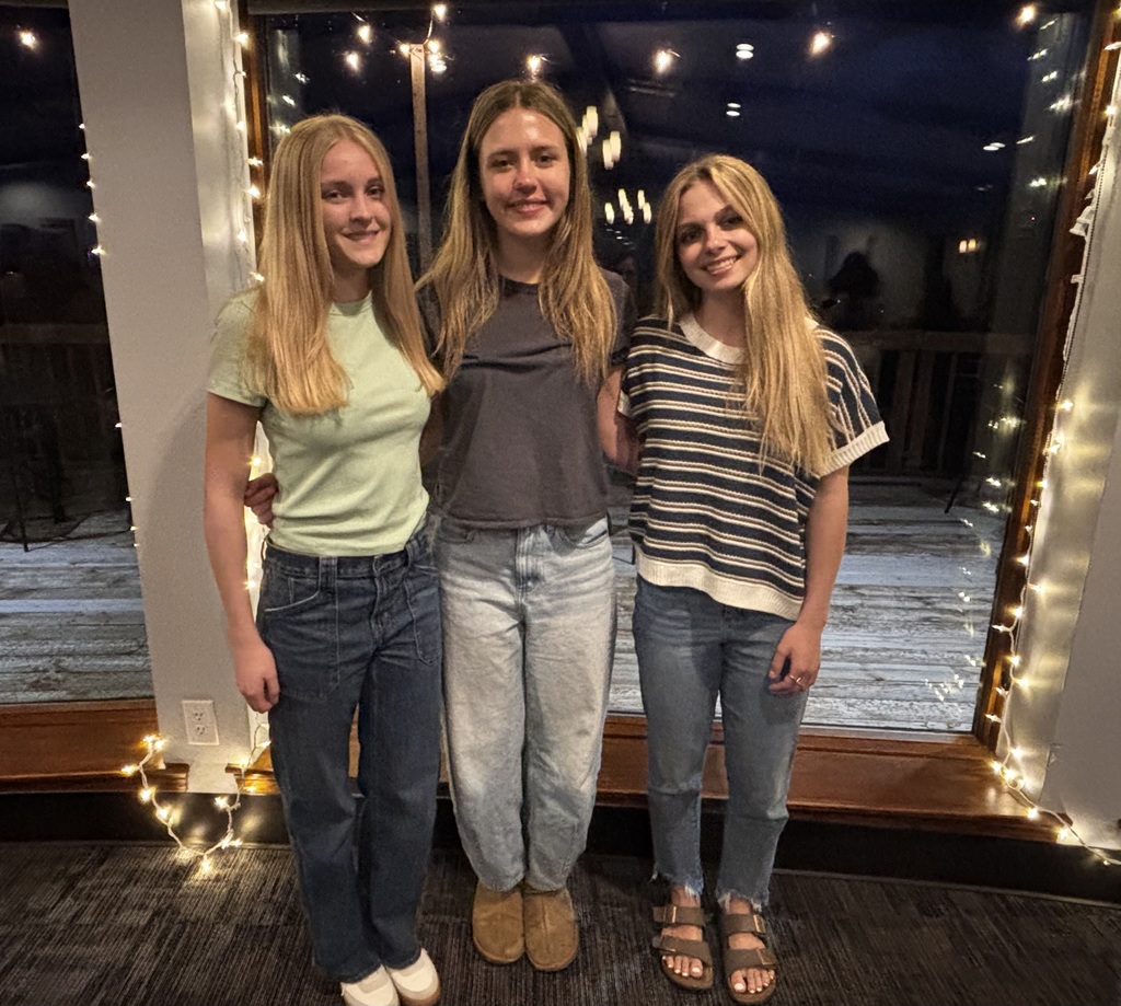 Senior basketball girls with picture window and white string lights in background