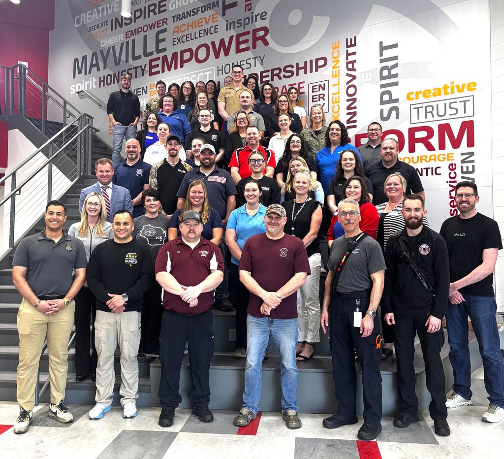 Group photo of smiling community partners standing on staircase in Cardinal Lobby entrance of Mayville High School