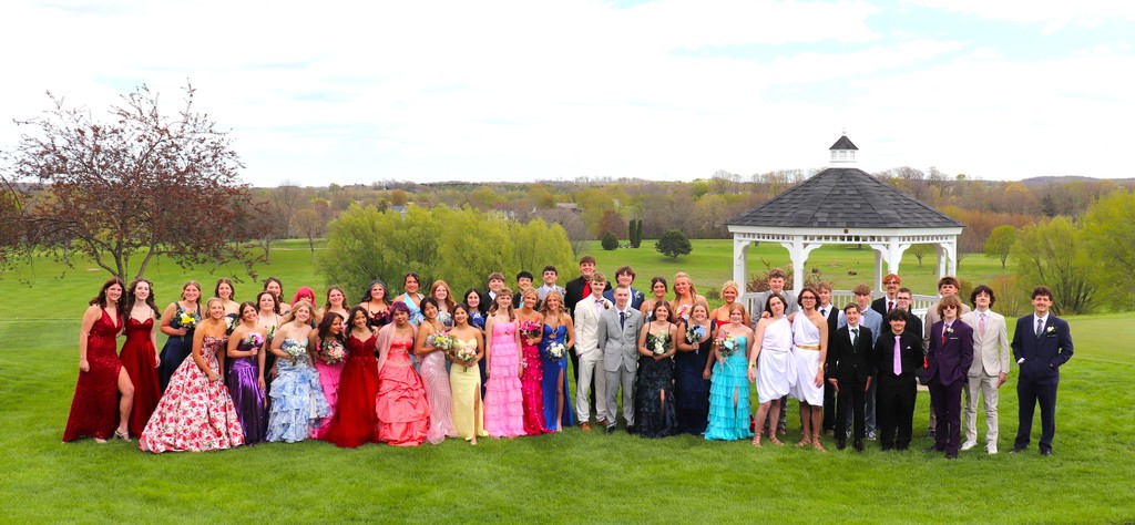 MHS Junior Class Prom Photo girls in formal dresses and boys in suits and togas on green grass with view of Mayville Golf Course
