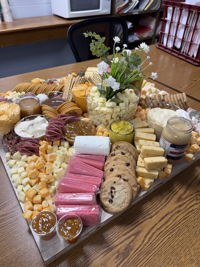 Charcuterie board with cheeses, meats, gourmet spreads and flower decor