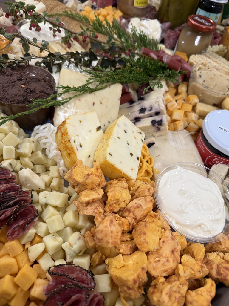 Charcuterie board with cheeses, meats, gourmet spreads and flower decor