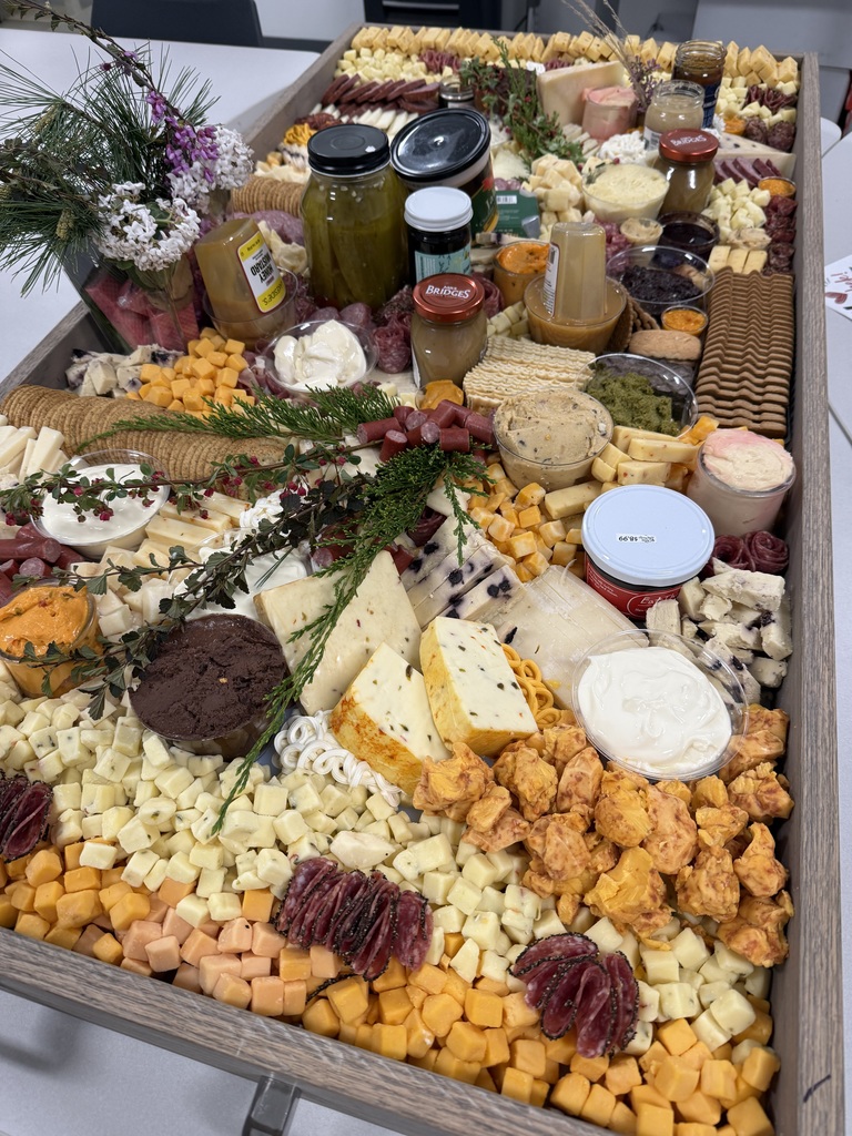 Charcuterie board with cheeses, meats, gourmet spreads and flower decor