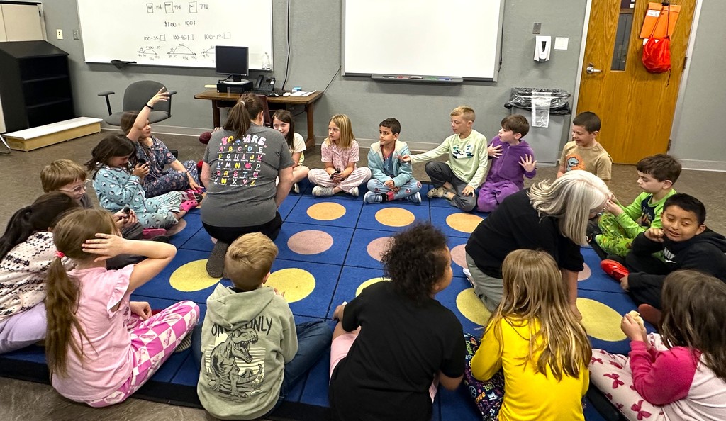 Children smiling and holding baby chicks, sitting on floor in classroom