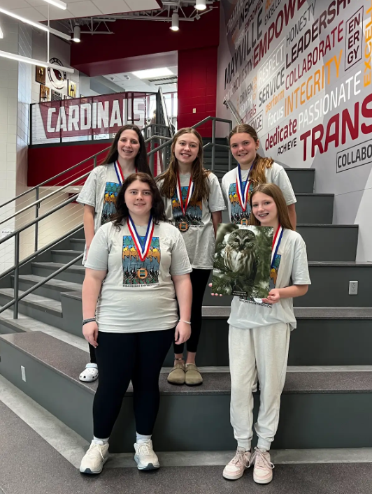 Middle school FFA members smiling on Cardinal Lobby staircase holding a rendering of an owl and wearing their medals