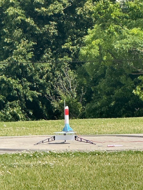 Summer school students out on lawn near school launching rockets and smiling