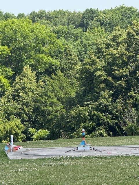 Summer school students out on lawn near school launching rockets and smiling